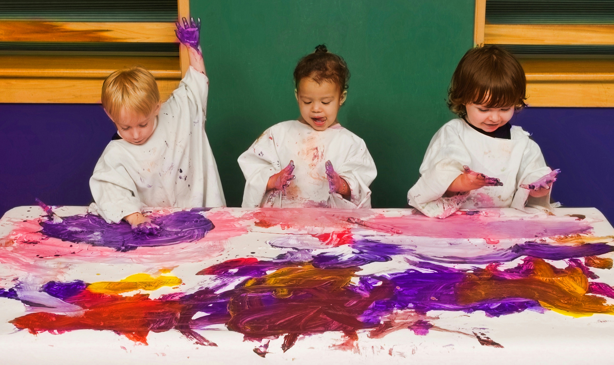 Toddlers in daycare fingerpaint with vibrant colors