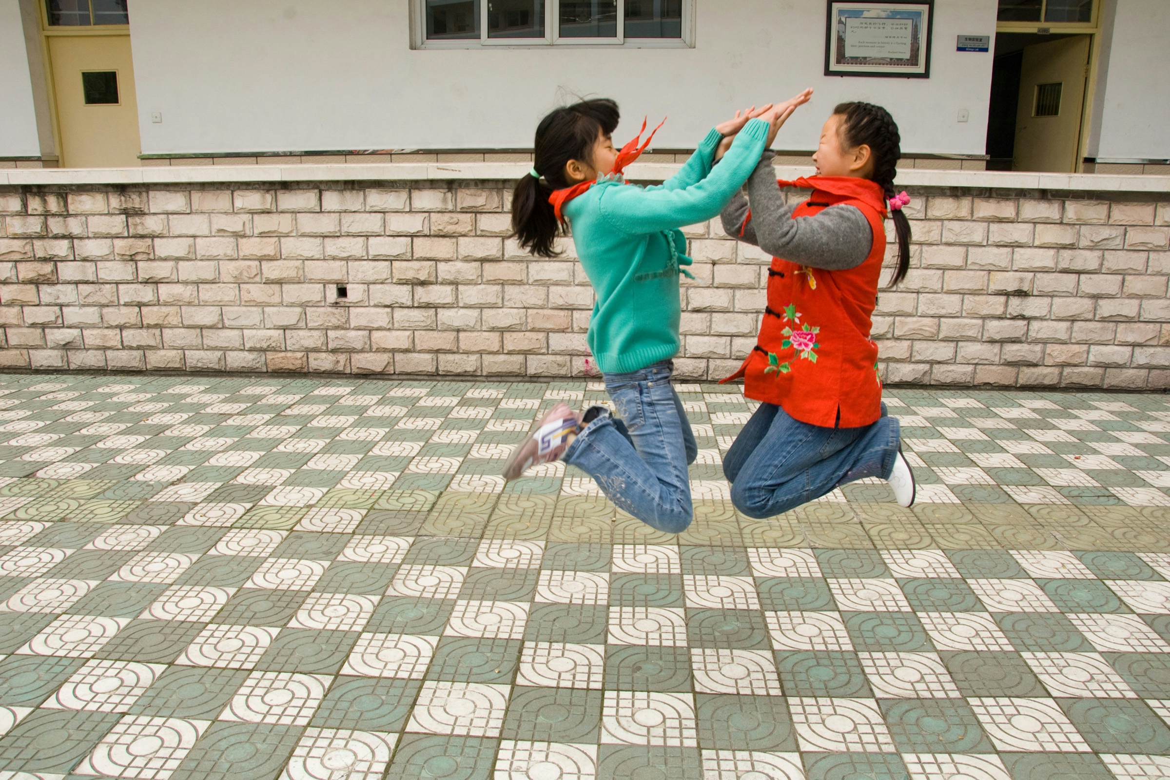 Two Chinese schoolgirls jump and clap in synchrony